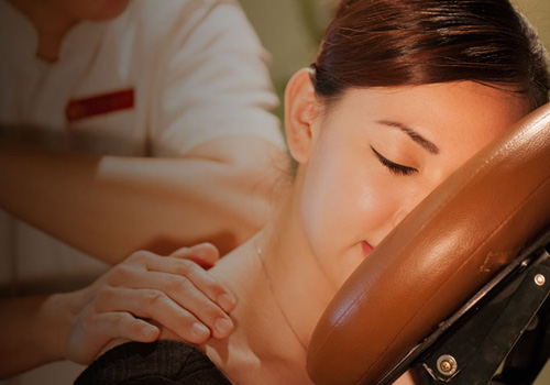 Woman enjoying signature seated chair massage at Kenko Wellness